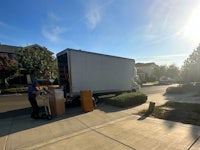 White truck in front of house, mover with two-wheels dolly 