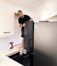 Handyman fixing an expensive fridge at kitchen with screwdriver